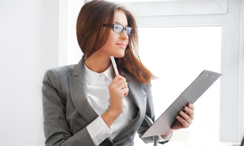 Beautiful business woman looking at papers she holding in her ar